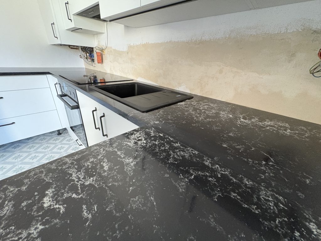 kuchnia wykończona blatami z konglomeratu Pearl Lava 3cm - widok na zlew i indukcję