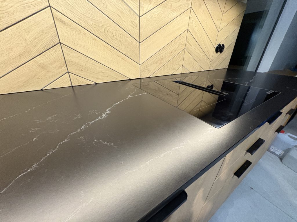 kuchenne blaty z konglomeratu nero venato w satynie - widok na kawałek blatu i kawałek indukcji licowanej z blatem