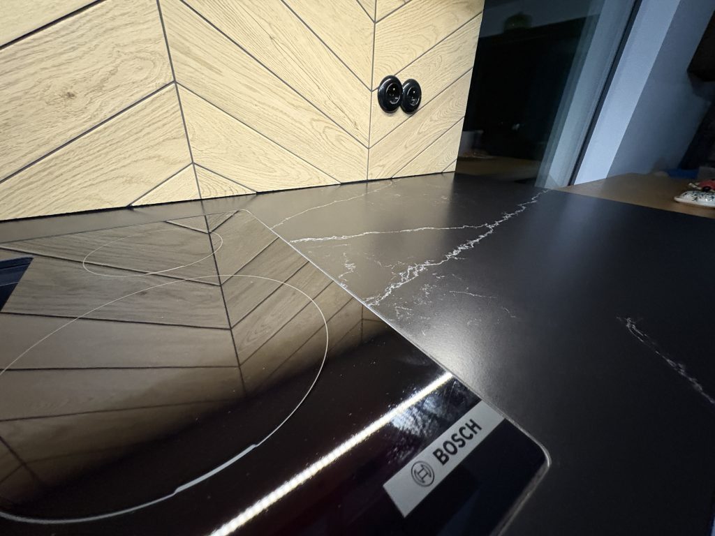 kuchenne blaty z konglomeratu nero venato w satynie - widok na kawałek indukcji licowanej z blatem