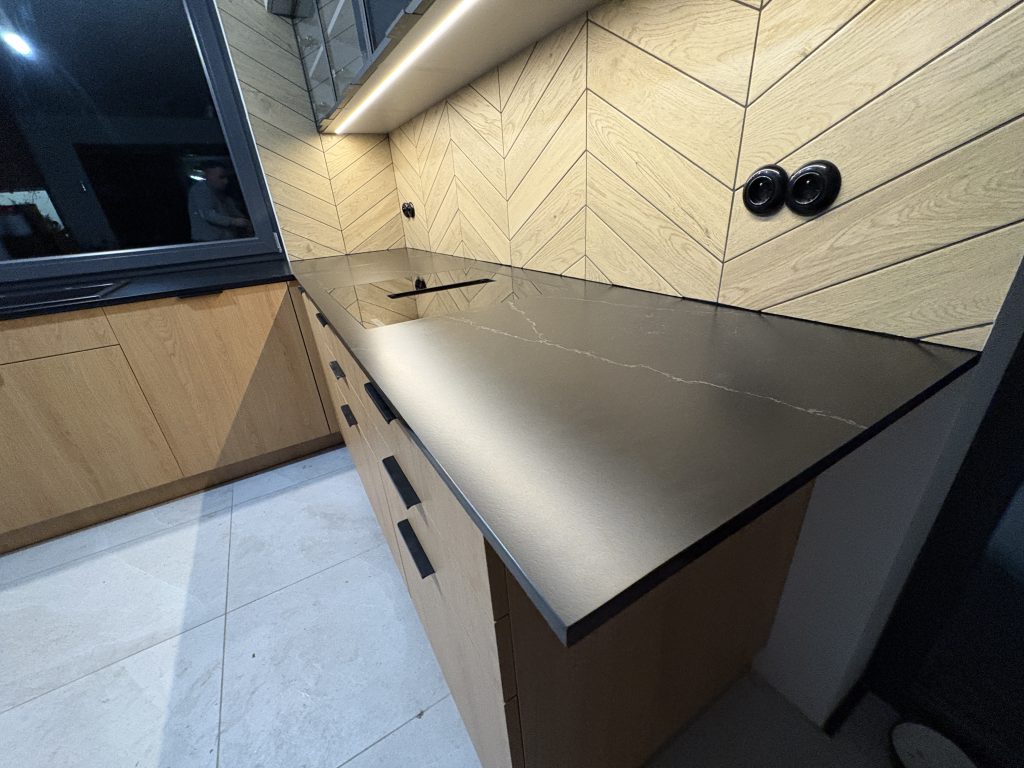 kuchenne blaty z konglomeratu nero venato w satynie - widok na blat z indukcją z prawej strony