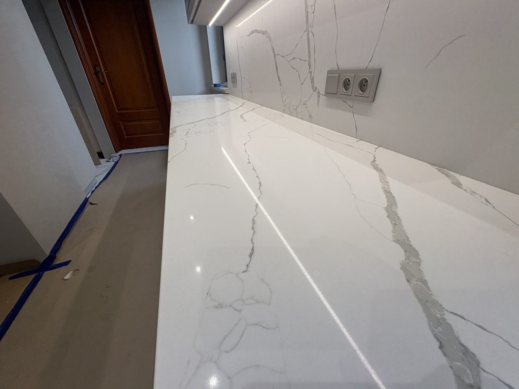 kuchnia wykończona konglomeratem kwarcowym Calacatta Silva - widok na blat roboczy i okładzinę z bliska z prawej strony