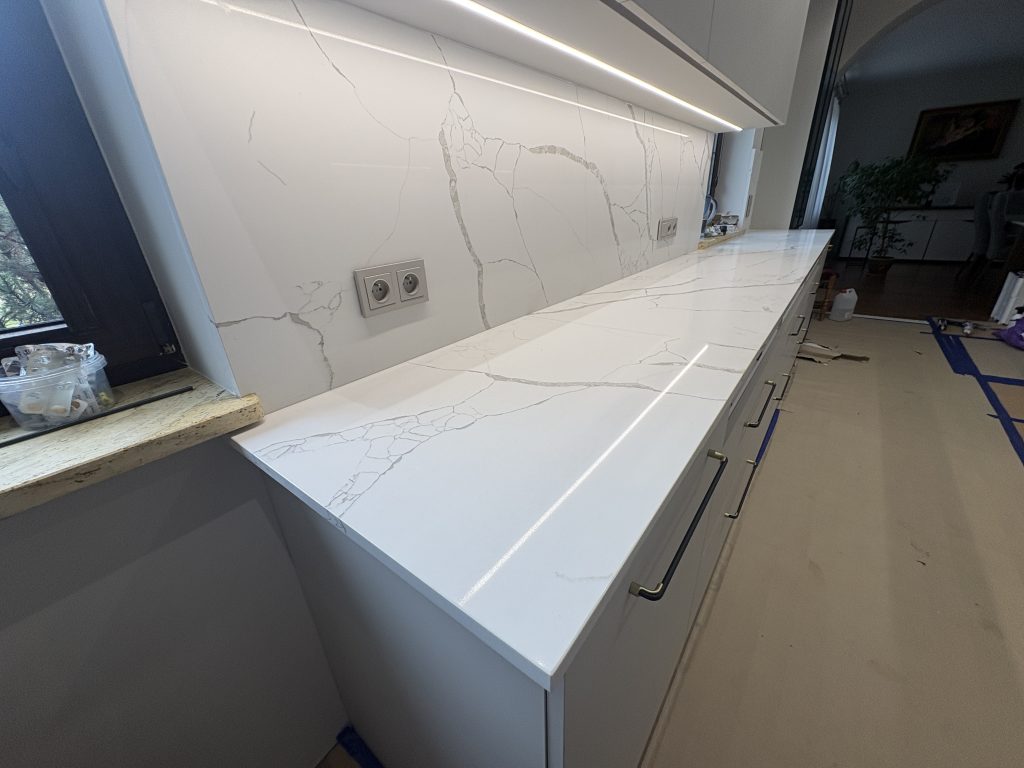 kuchnia wykończona konglomeratem kwarcowym Calacatta Silva - widok na blat roboczy i okładziną z lewej strony