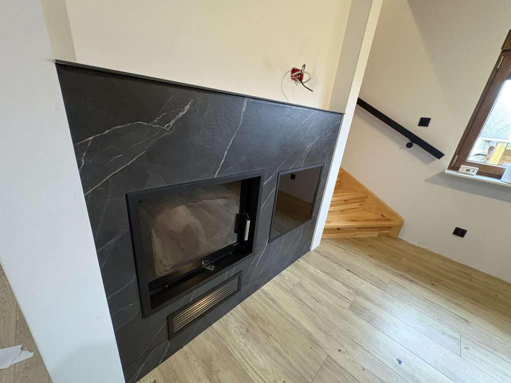 kominek wykończony spiekiem Calacatta Black Bocciardato - widok z lewej strony