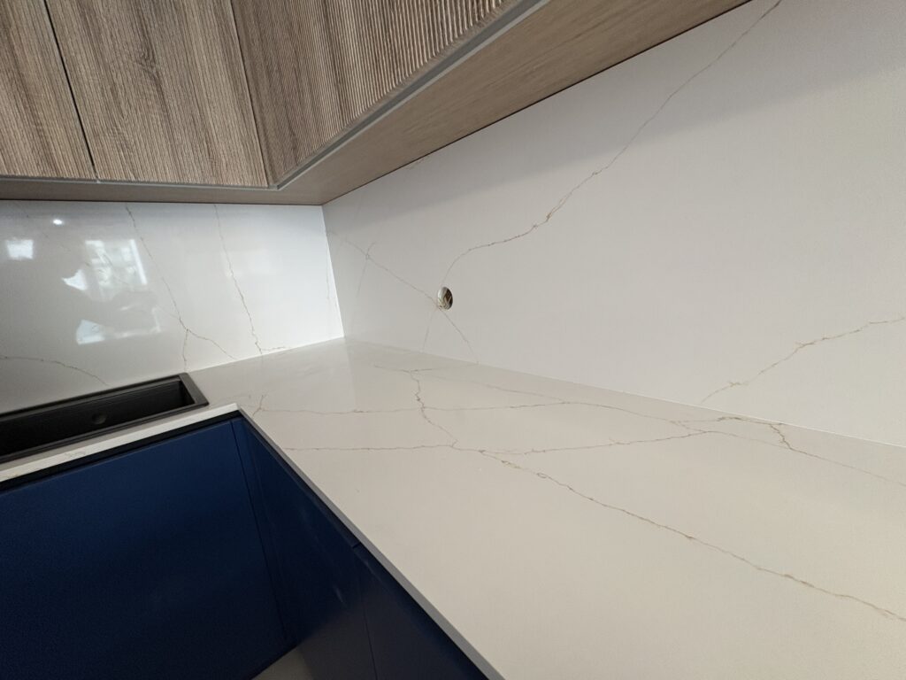 kuchnia wykończona blatami i okładzinami z konglomeratu Calacatta Gold - widok na łączenie blatów i okładzin