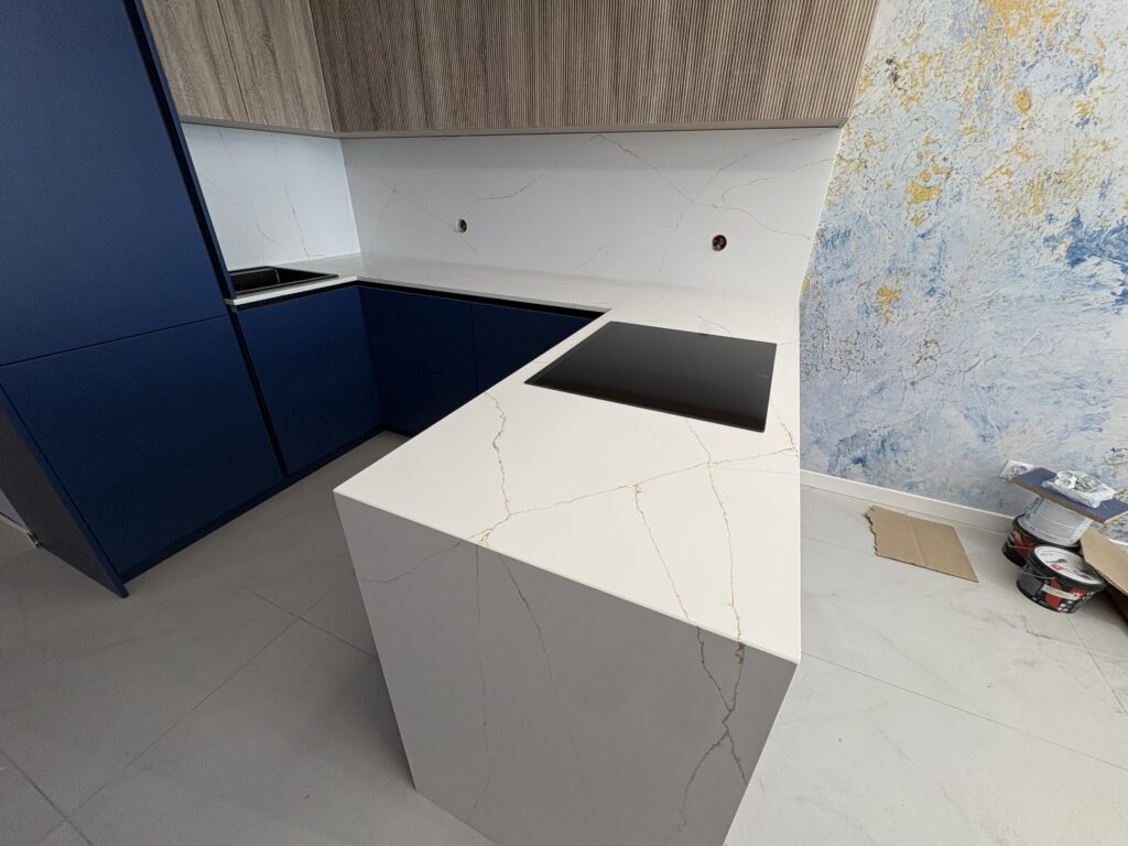 kuchnia wykończona blatami i okładzinami z konglomeratu Calacatta Gold - widok na całość z bliska