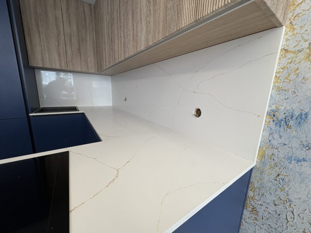 kuchnia wykończona blatami i okładzinami z konglomeratu Calacatta Gold - widok na jeden z blatów i okładzinę z prawej strony