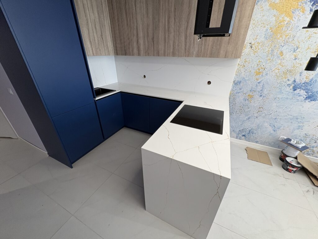 kuchnia wykończona blatami i okładzinami z konglomeratu Calacatta Gold - widok na całość z daleka