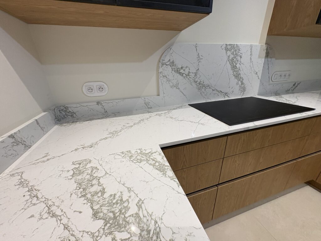 kuchnia wykończona konglomeratem Verde Peak - widok na łączenie blatów oraz płytę indukcyjną i okładzinę ścienną za nią