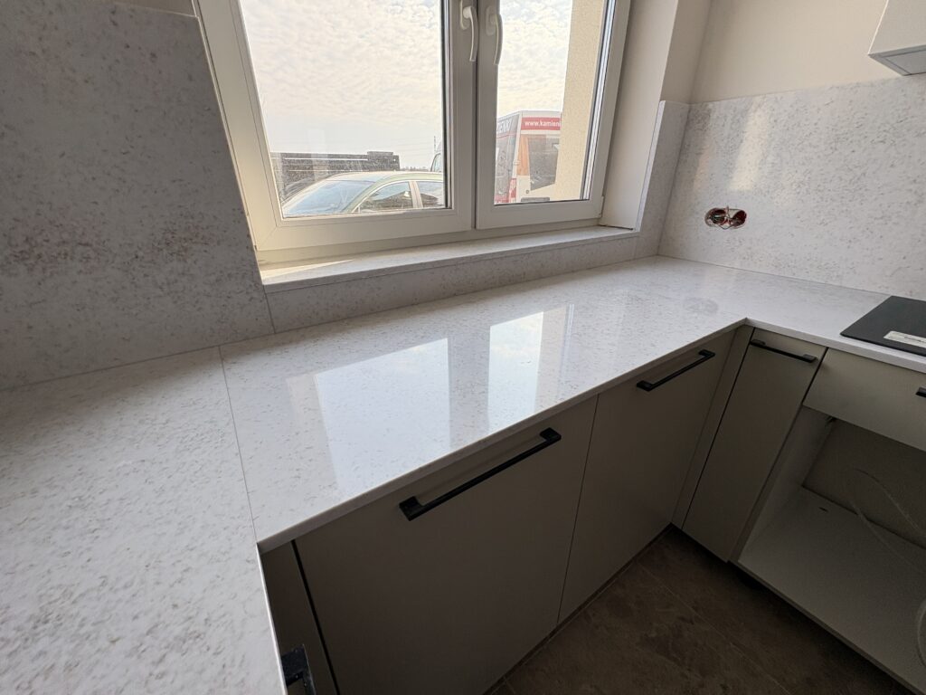 kuchnia wykończona konglomeratem Wedding Lily - widok na blat pod oknem, parapet i podparapet