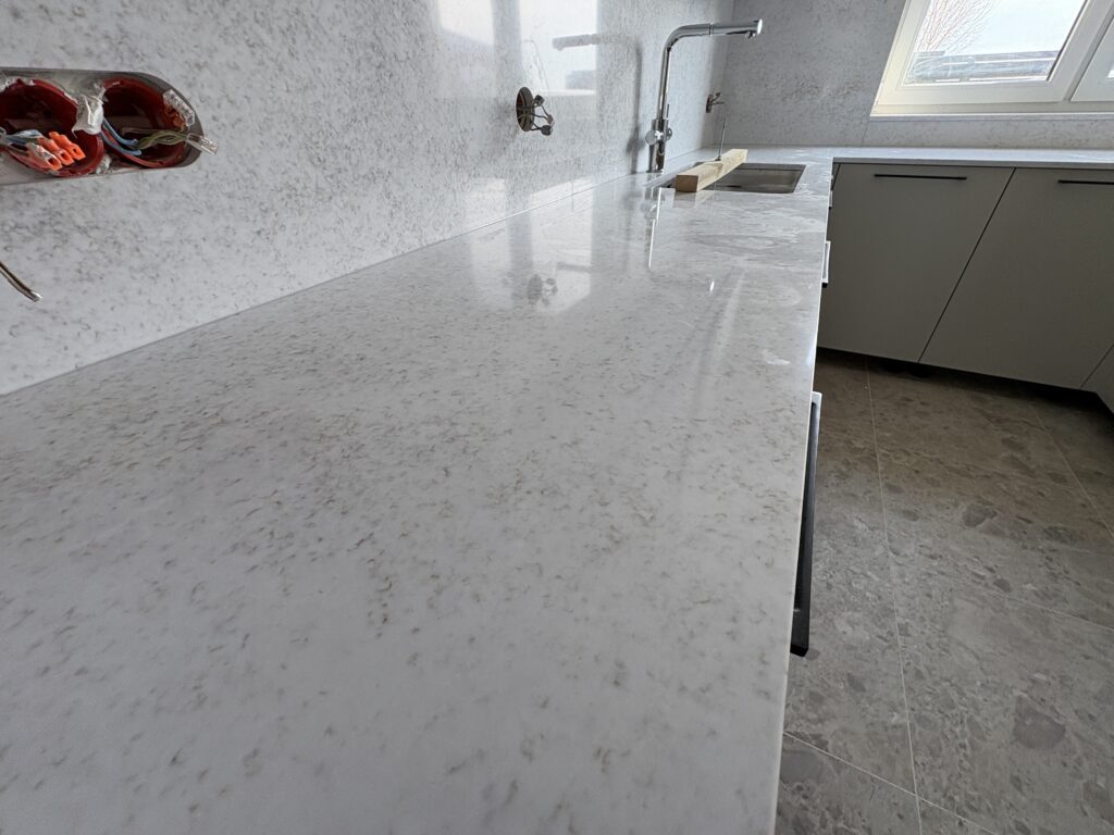 kuchnia wykończona konglomeratem Wedding Lily - widok dług blat ze zlewem i okładzinę