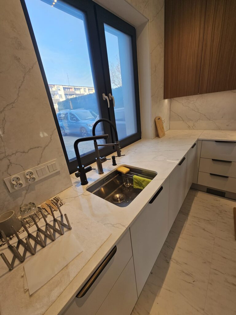 kuchnia wykończona blatami i okładzinami ściennymi z konglomeratu Calacatta Concorde - widok na zlew podwieszany