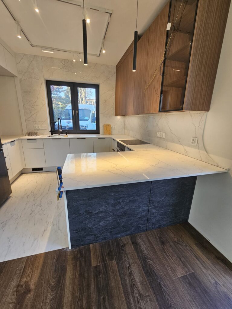 kuchnia wykończona blatami i okładzinami ściennymi z konglomeratu Calacatta Concorde - widok na całość z bliska