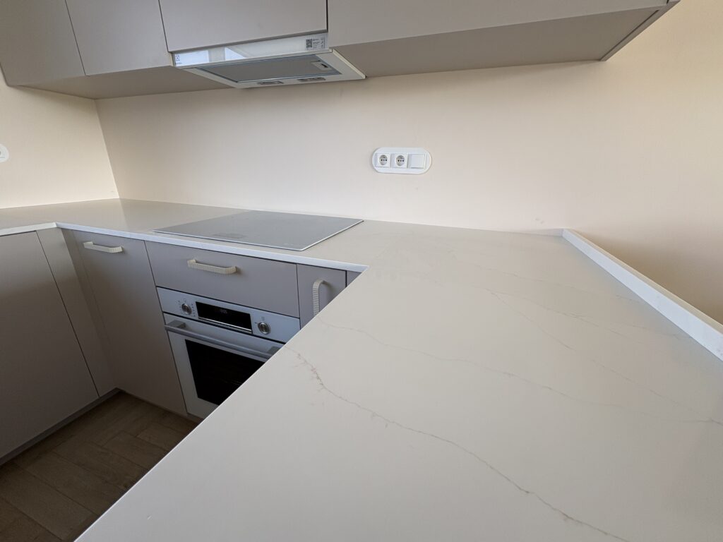 blaty kuchenne - konglomerat Calacatta Cannes Gold - widok na łączenie blatu z płytą indukcyjną oraz blat na wyspie