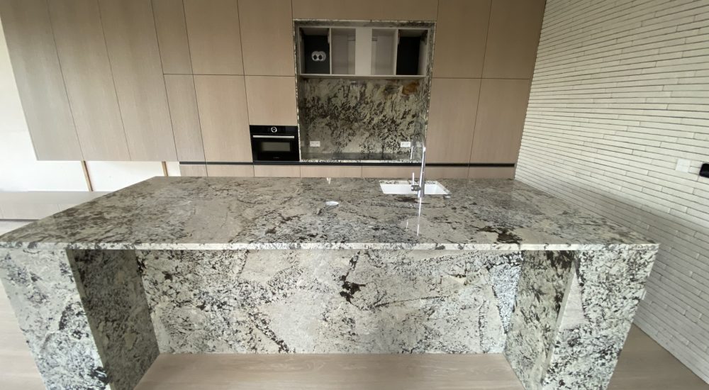 kuchnia wykończona kamiennymi blatami i okładzinami z granitu